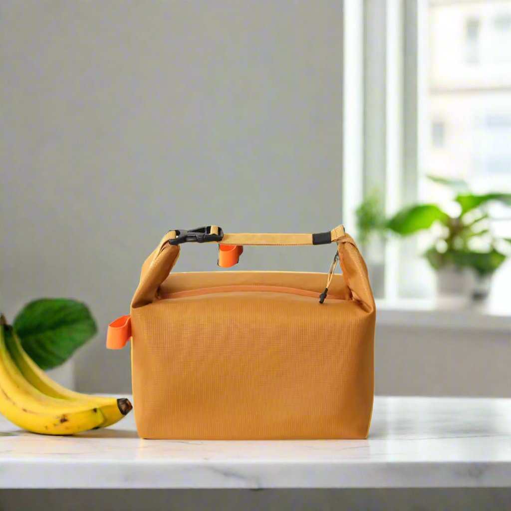 Yellow adult lunch tote bag on a kitchen counter with bananas and greenery in the background.