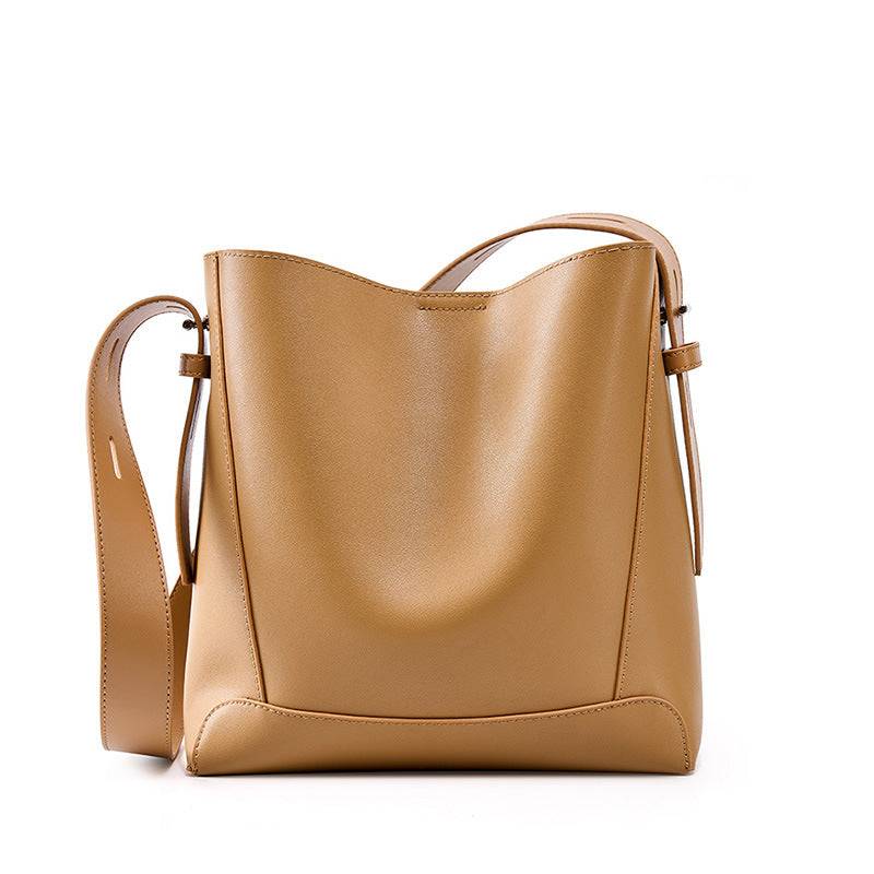 Tan leather bucket tote purse with shoulder strap.