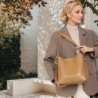 Woman holding a tan Bucket Tote Purse made of genuine leather, showcasing its elegant design and spacious interior.