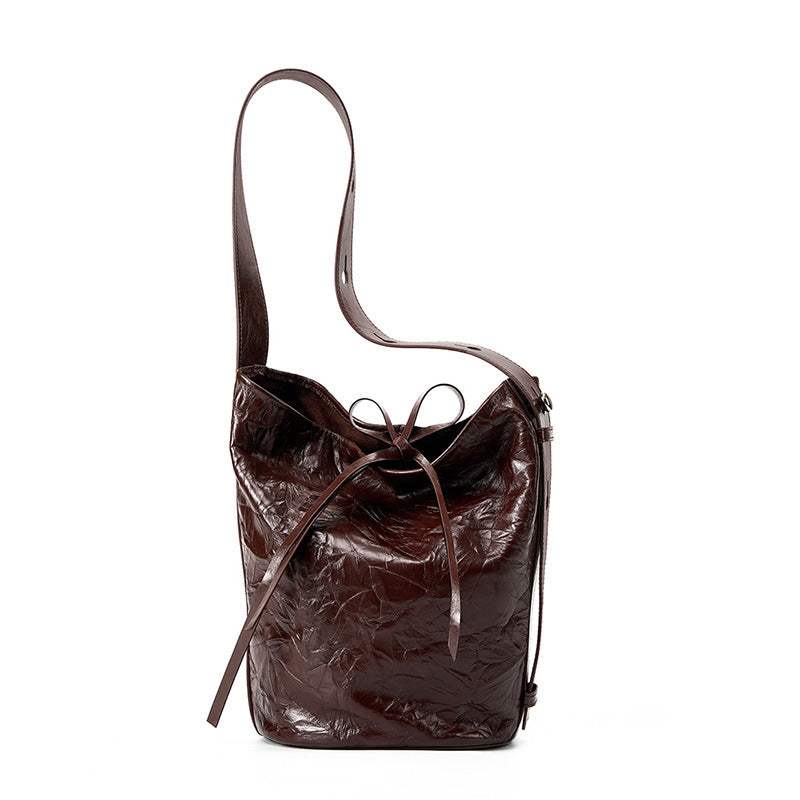 Burgundy bucket bag with wrinkled leather, shoulder strap, and tie closure.