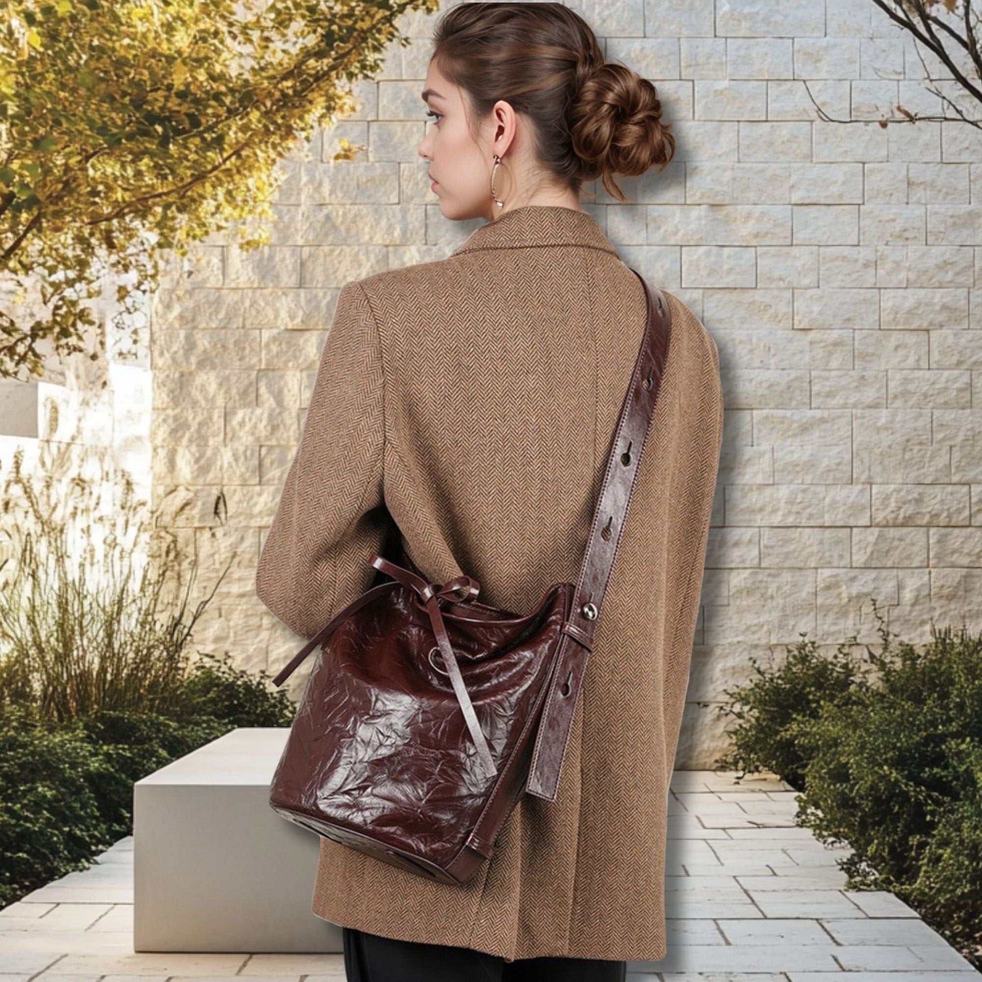 Burgundy Bucket Bag in genuine leather with elegant wrinkled pattern, shown on a person wearing a coat.