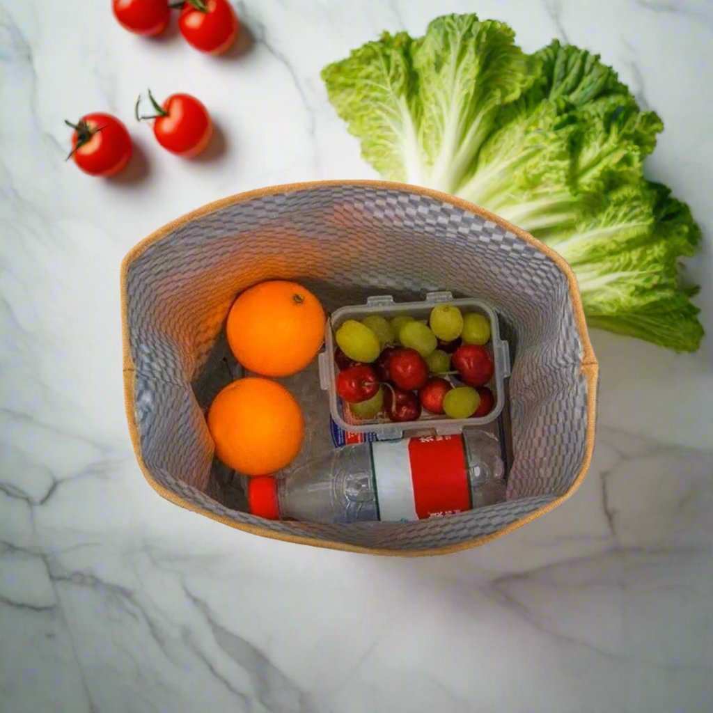 Stylish waxed canvas lunch bag with waterproof interior holding fresh fruits and vegetables.