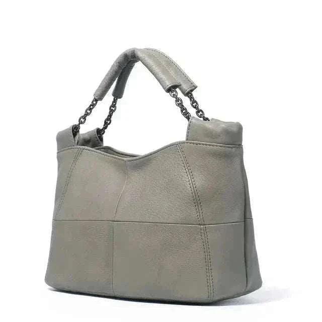 Crossbody soft leather bag with chain-link handle and decorative stitching.