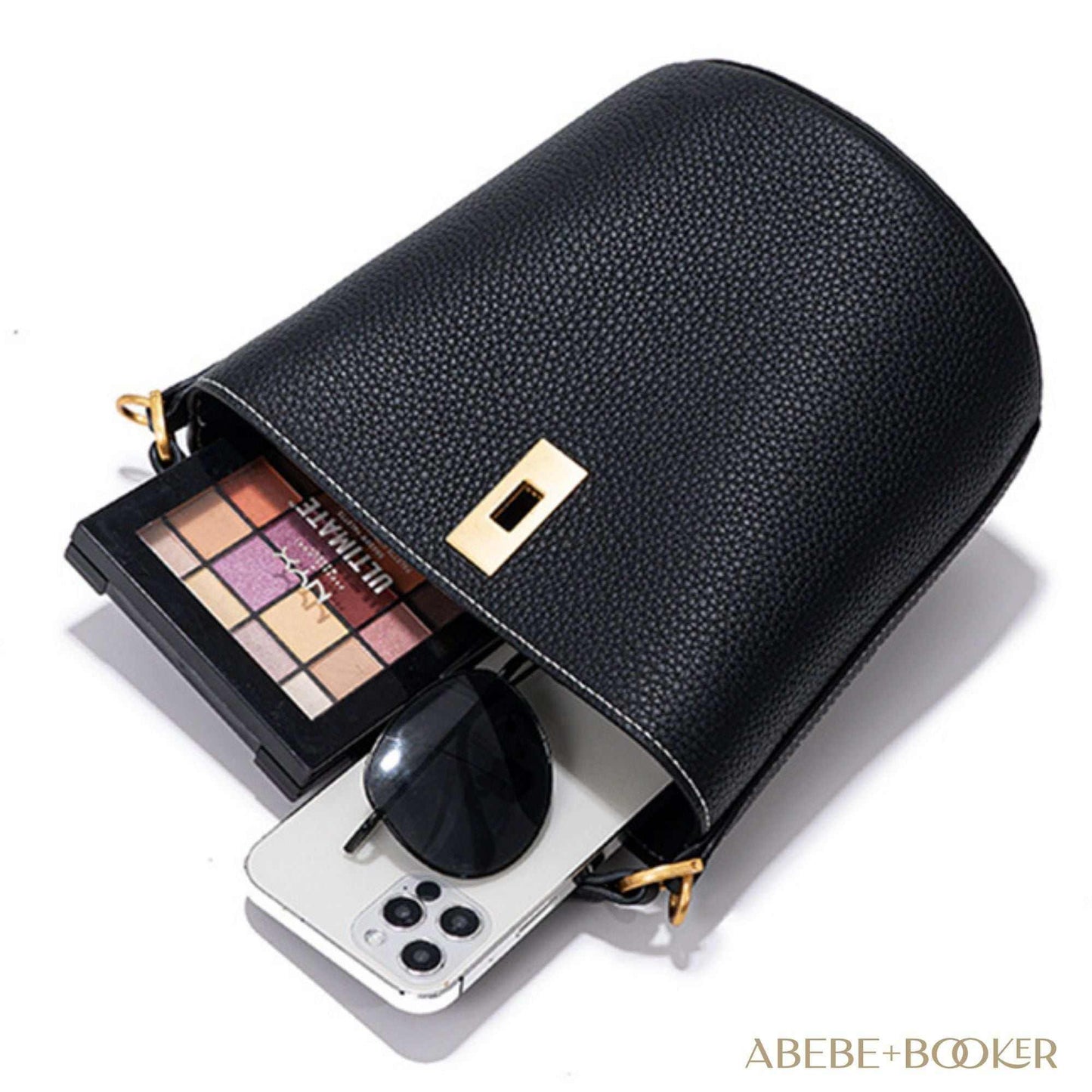 Black crossbody bucket purse with makeup palette and phone inside, made from genuine leather.