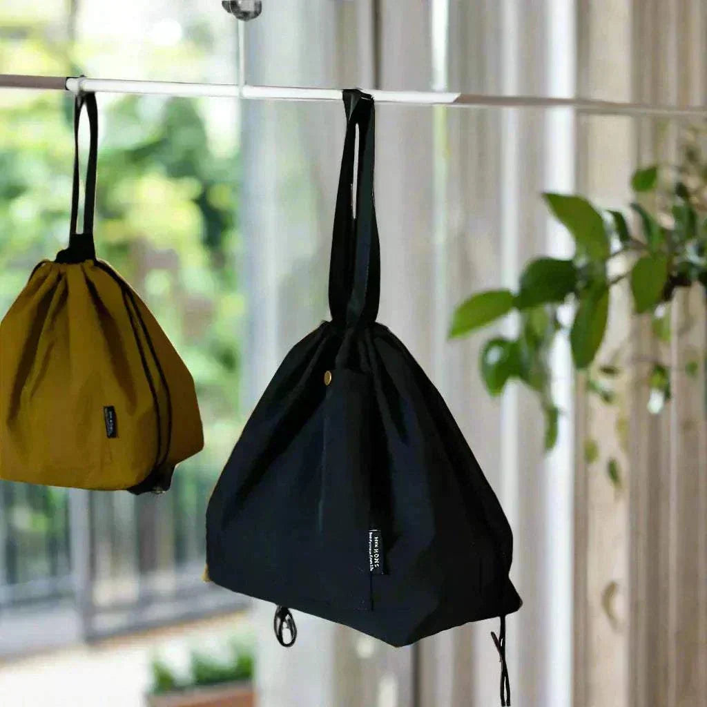 Insulated lunch pouches hanging by handles, showcasing drawstring closure and durable canvas material.