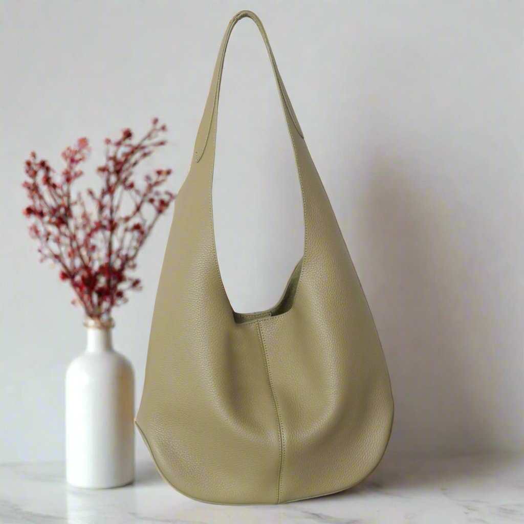 Large leather tote bag in light olive color, showcasing a simple and relaxed design.