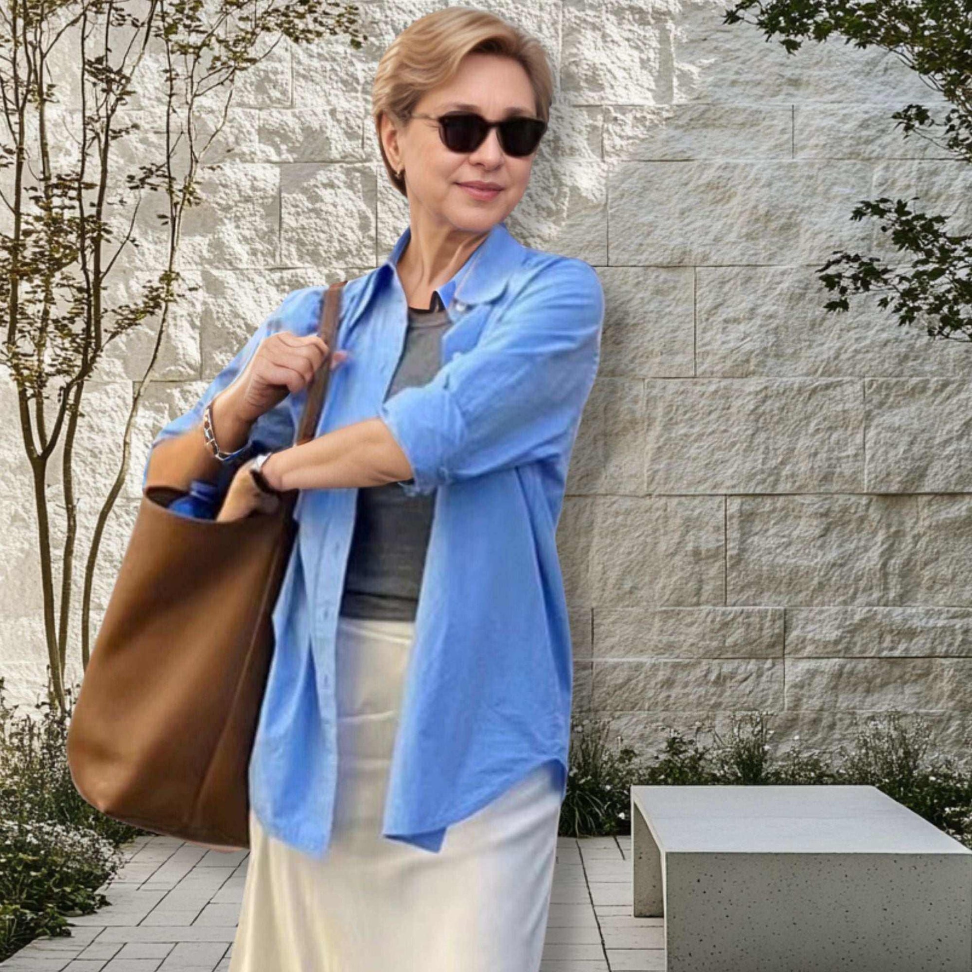 Woman holding Iconic Leather Bucket Bag Lychee in garden setting.