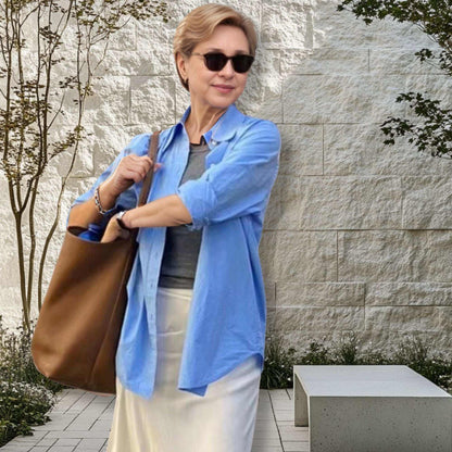 Woman holding Iconic Leather Bucket Bag Lychee in garden setting.