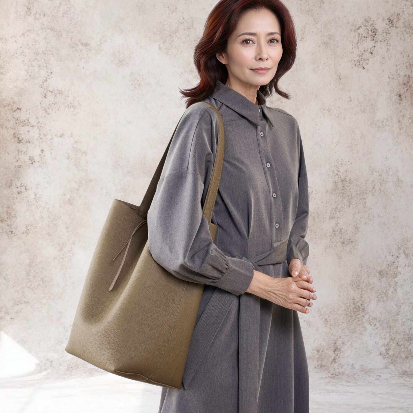 Elegant woman holding Iconic Leather Bucket Bag in lychee pattern, showcasing luxury and practicality.