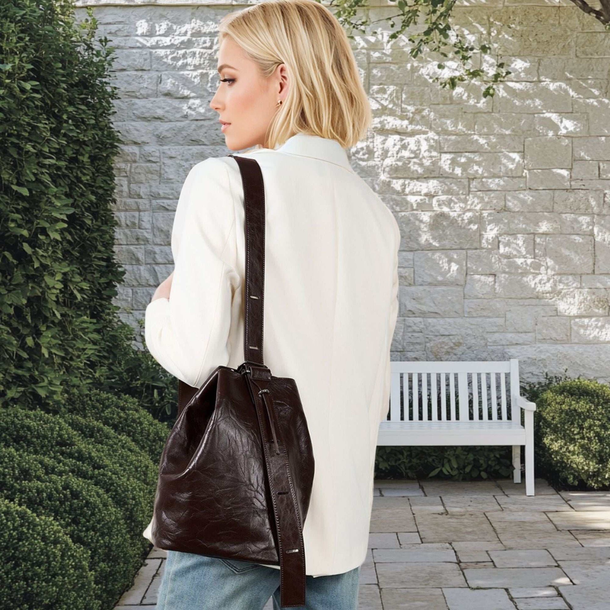 Woman wearing a leather convertible backpack outdoors.