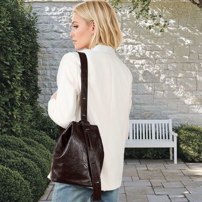 Woman wearing a leather convertible backpack outdoors.