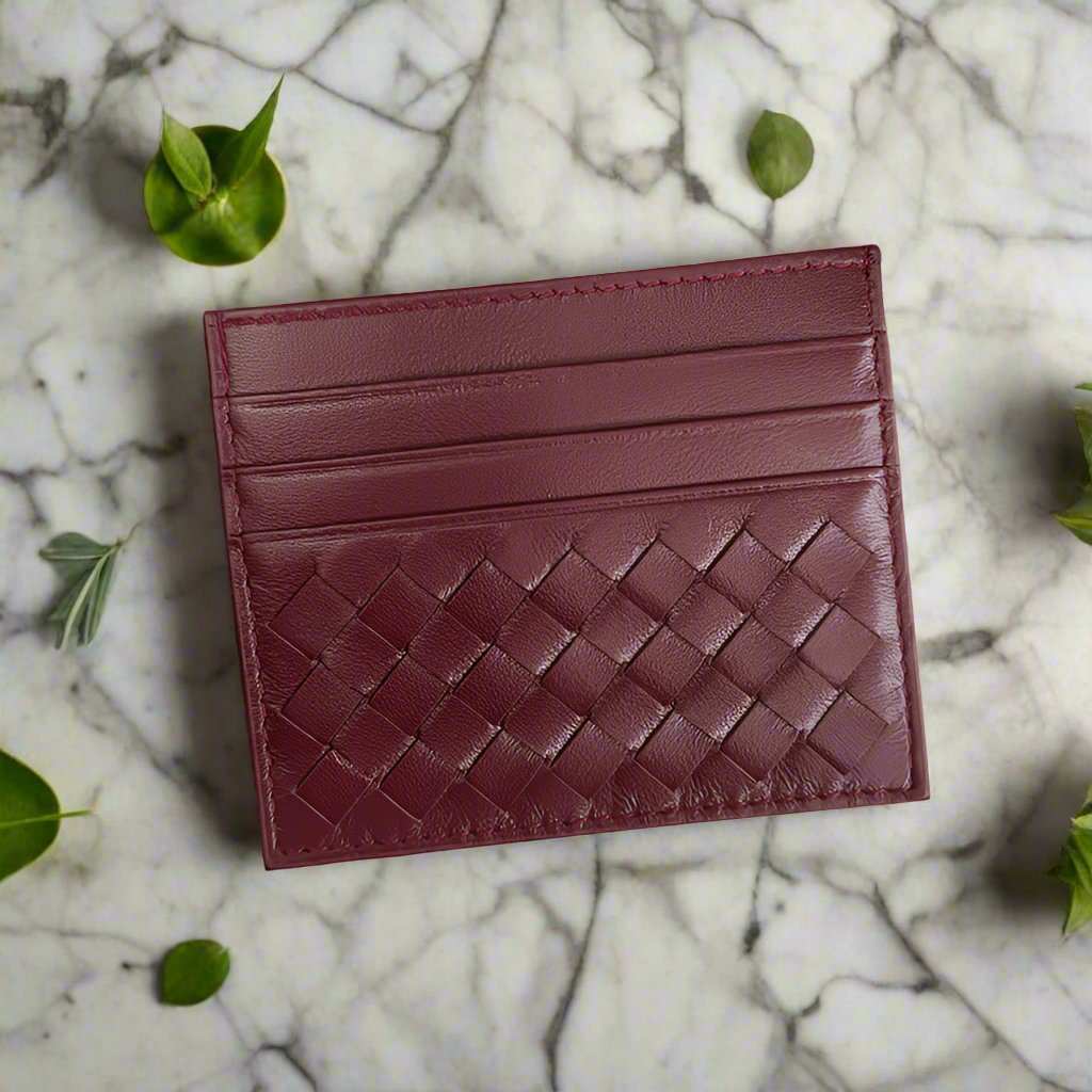 Burgundy woven leather credit card carrier on marble surface.