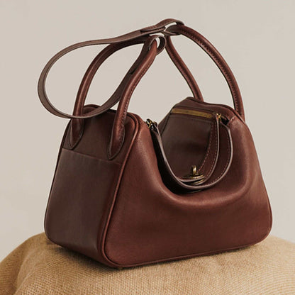 Brown leather satchel purse with double handles and zipper closure, luxurious and stylish.