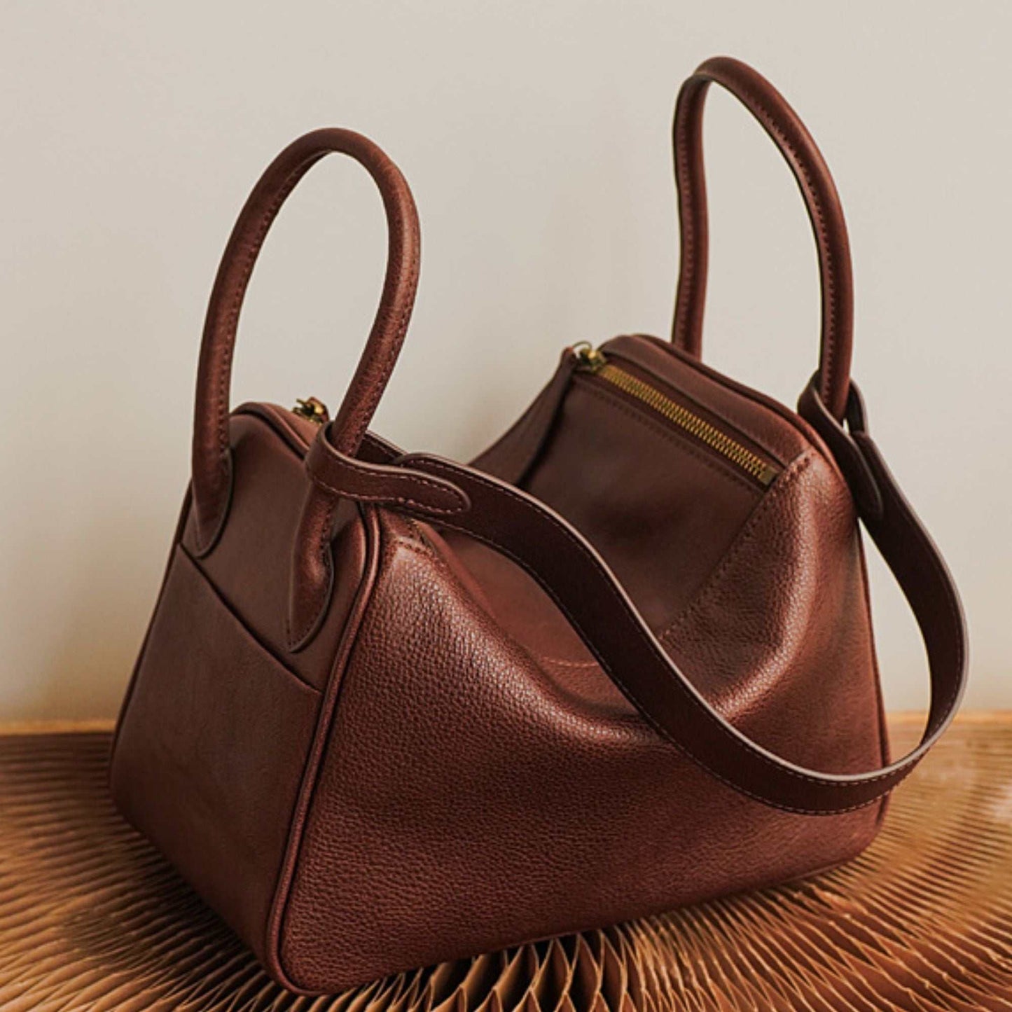 Brown leather satchel purse with double handles and zipper closure.