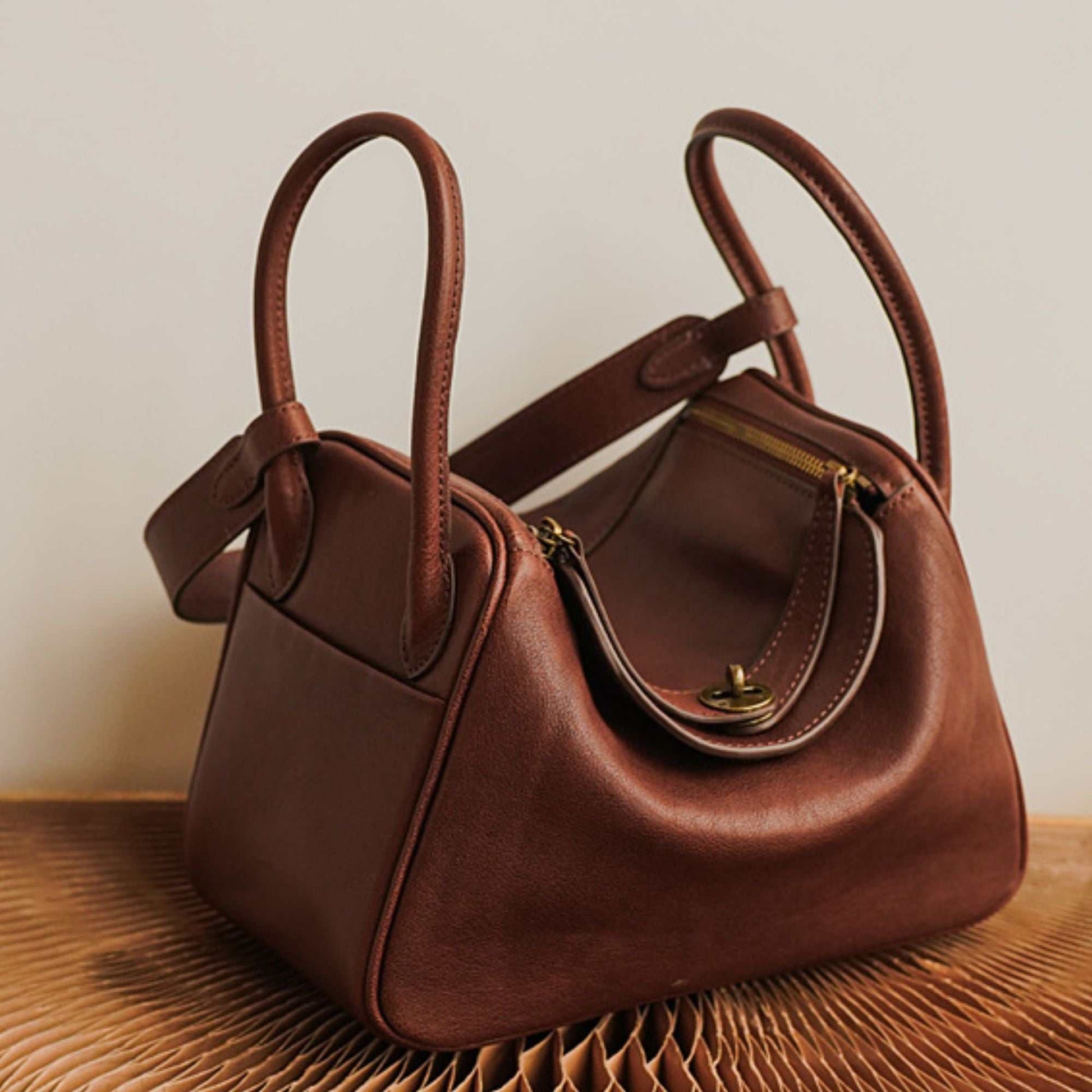 Brown Leather Satchel Purse with handles and zipper closure on textured surface.