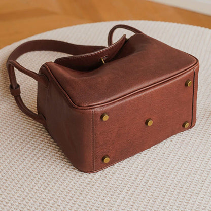 Brown Leather Satchel Purse on beige surface displaying base details.