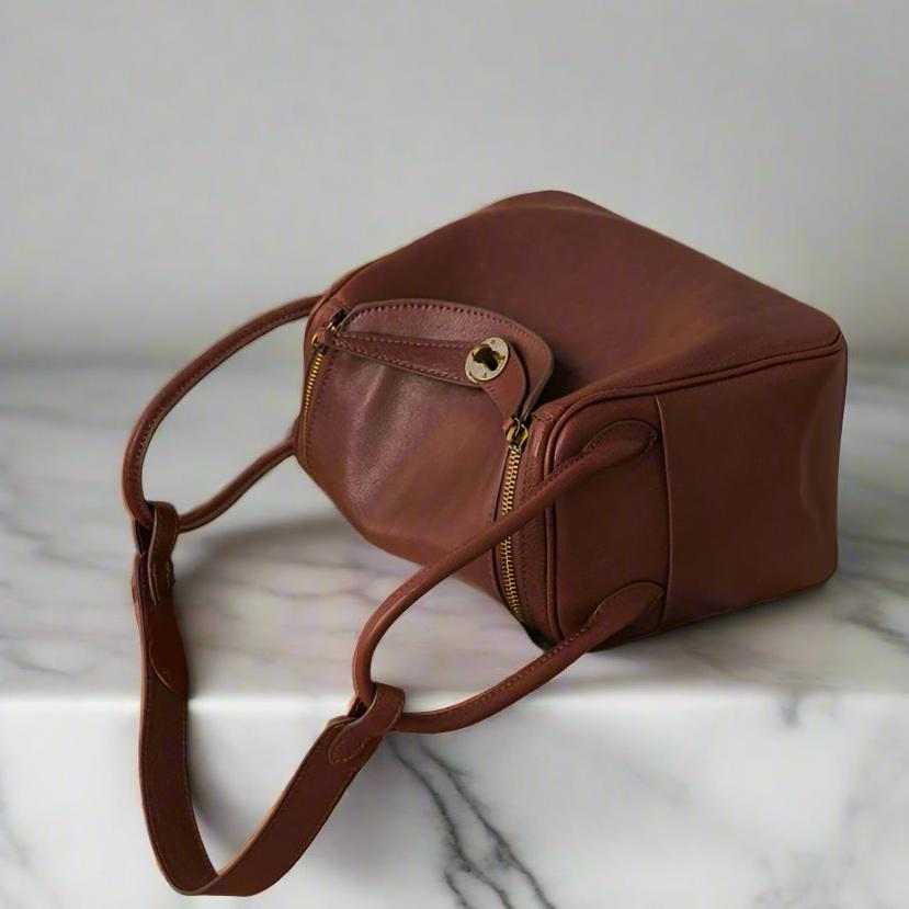 Leather satchel purse with a soft brown finish on a marble surface.