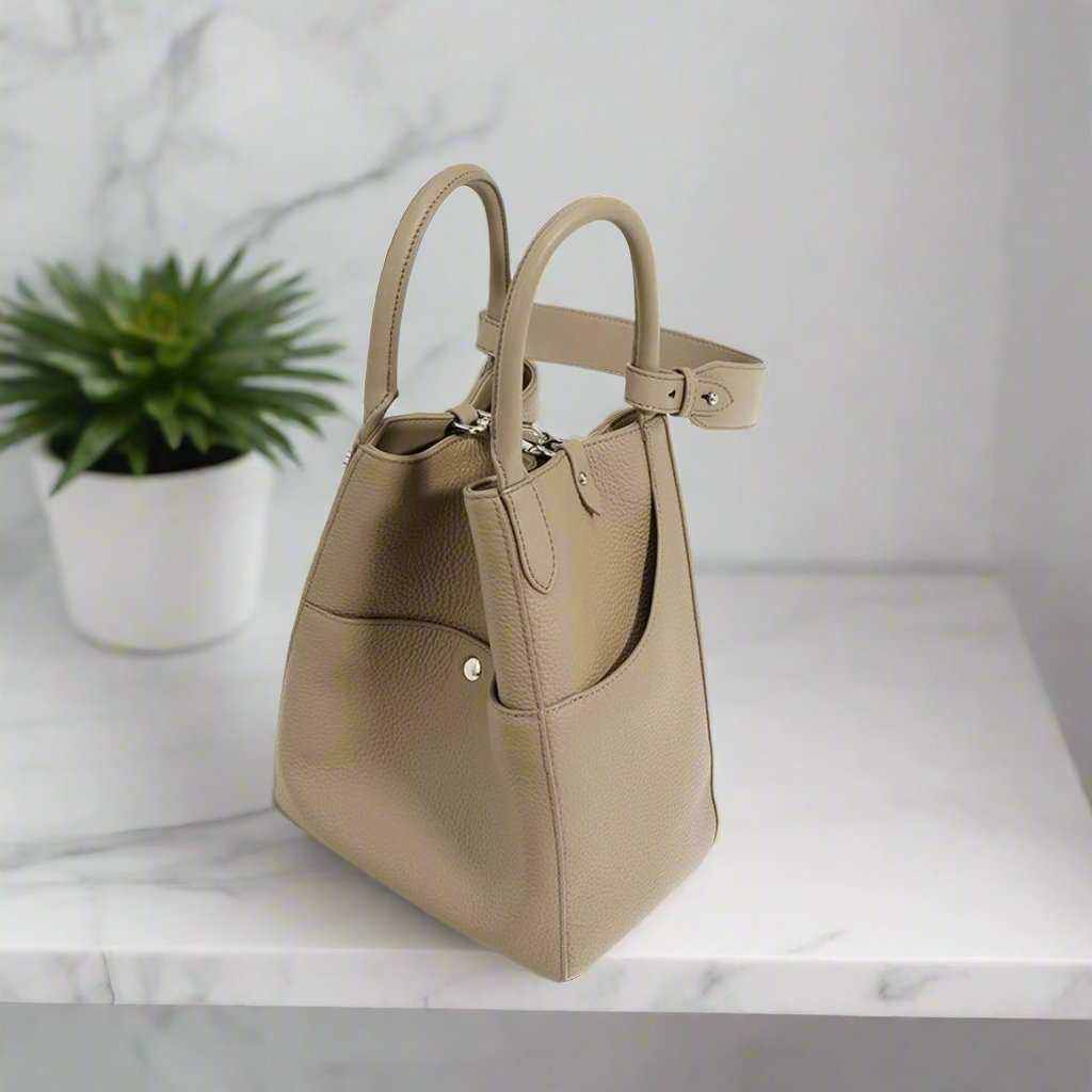 Luxurious leather tote bag crossbody on a marble surface with a white planter in the background.