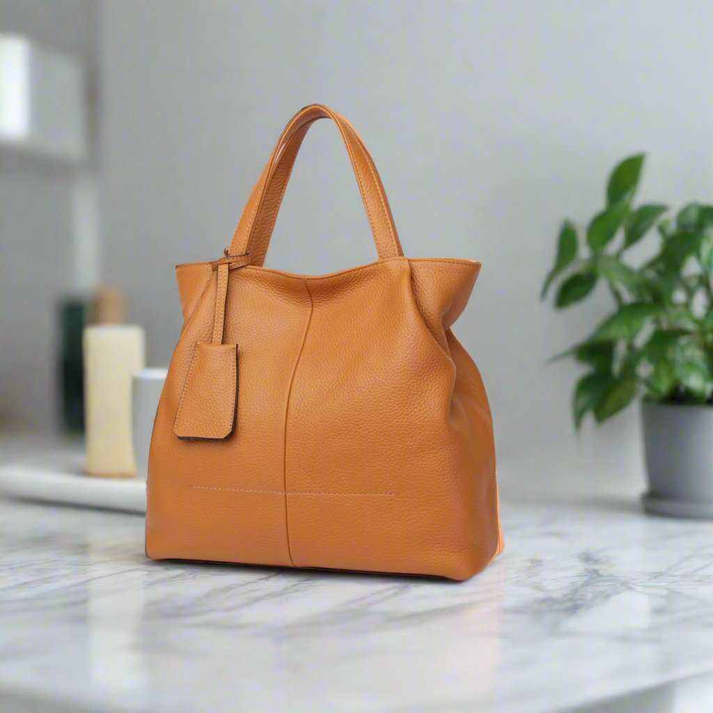 Luxurious genuine leather tote zipper handbag on marble surface, featuring a spacious design and elegant style.