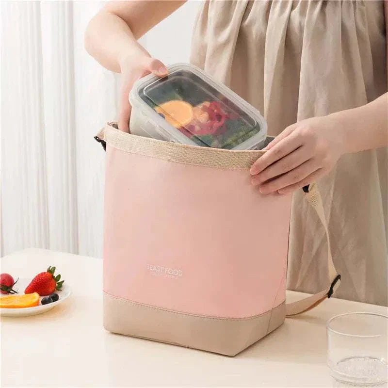 Pink lunch tote with shoulder strap, durable Oxford cloth, woman packing food container.