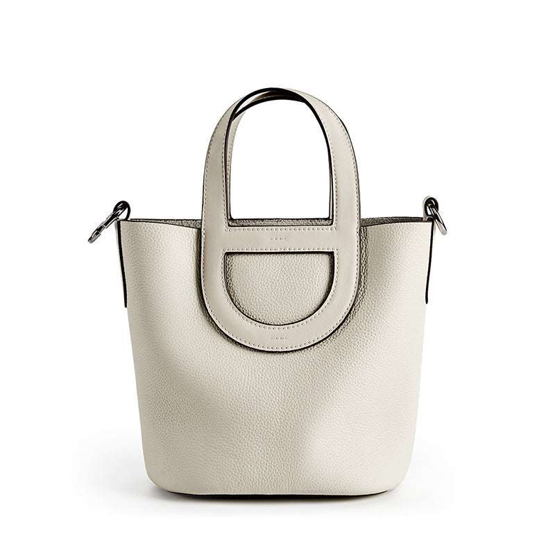 Sleek leather bucket handbag with lychee-pattern and removable strap, genuine leather material, eco-friendly accessory.