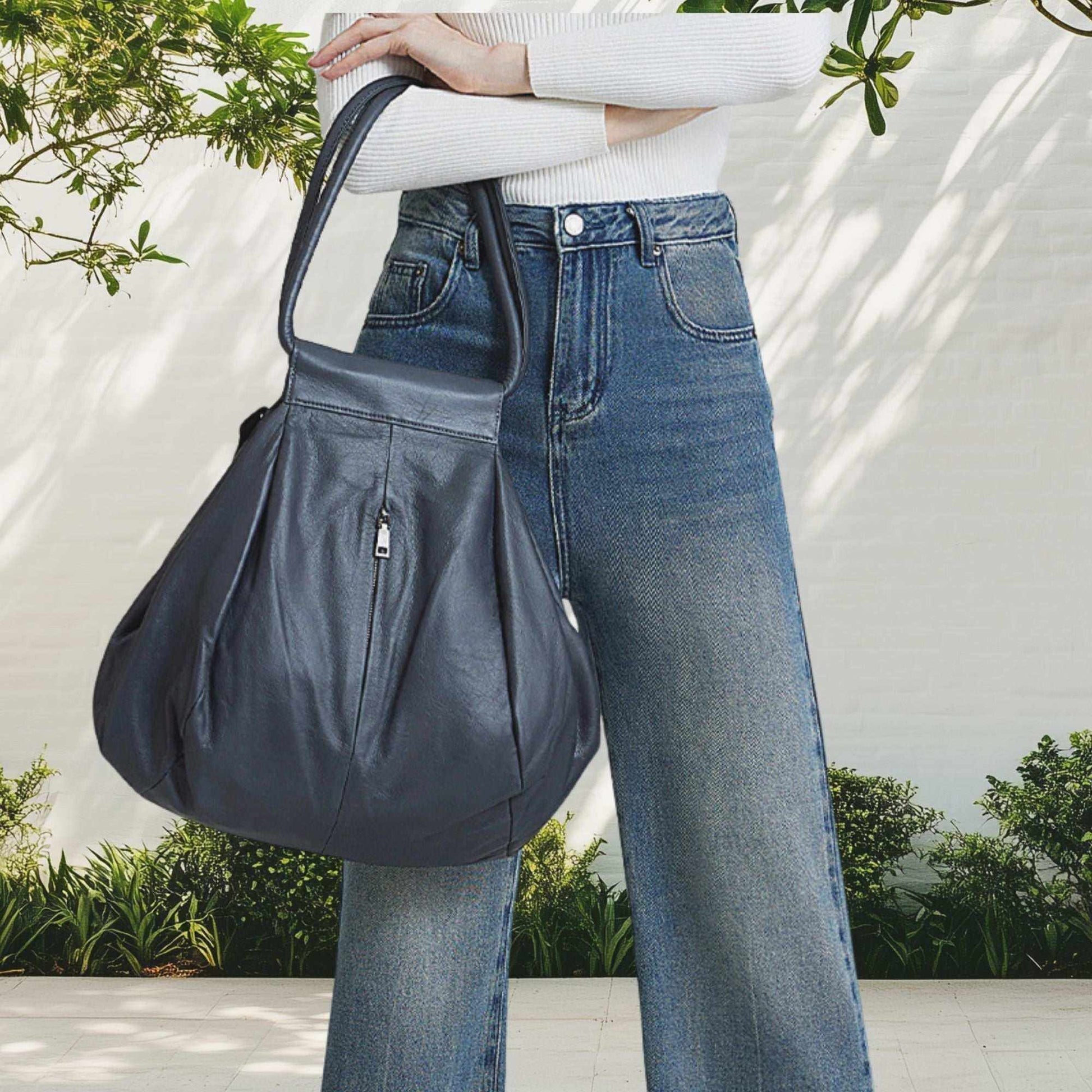 Genuine Leather Slouchy Bag in Dark Blue, stylish versatility, held as a shoulder bag, outdoor casual setting.