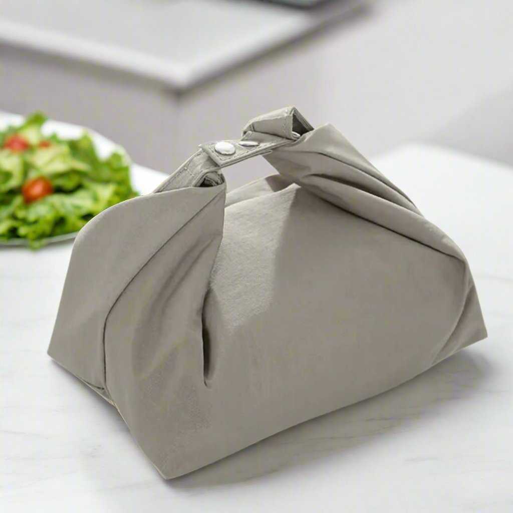 Small waterproof and insulated lunch bag in sleek design on a table with salad.