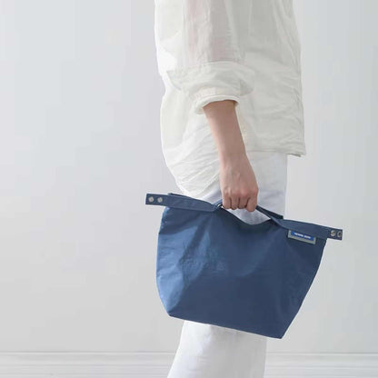 Small lunch bag in elegant blue, water-resistant, thermal insulated, versatile carrying design.