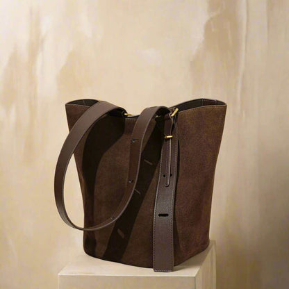 Suede bucket bag on display, featuring durable nubuck leather, convertible design, and spacious interior.