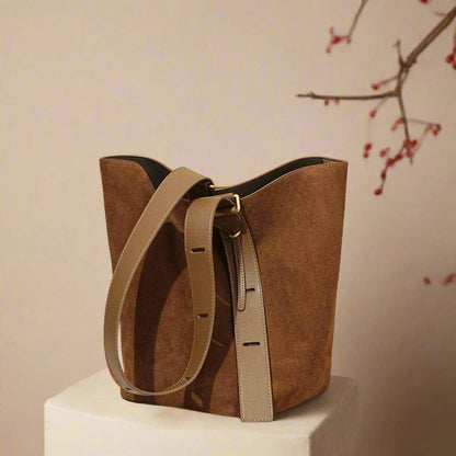 Suede bucket bag with adjustable strap on display.