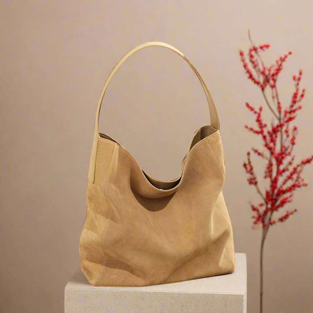 Suede Slouch Bag with single-shoulder design, displayed on a pedestal.