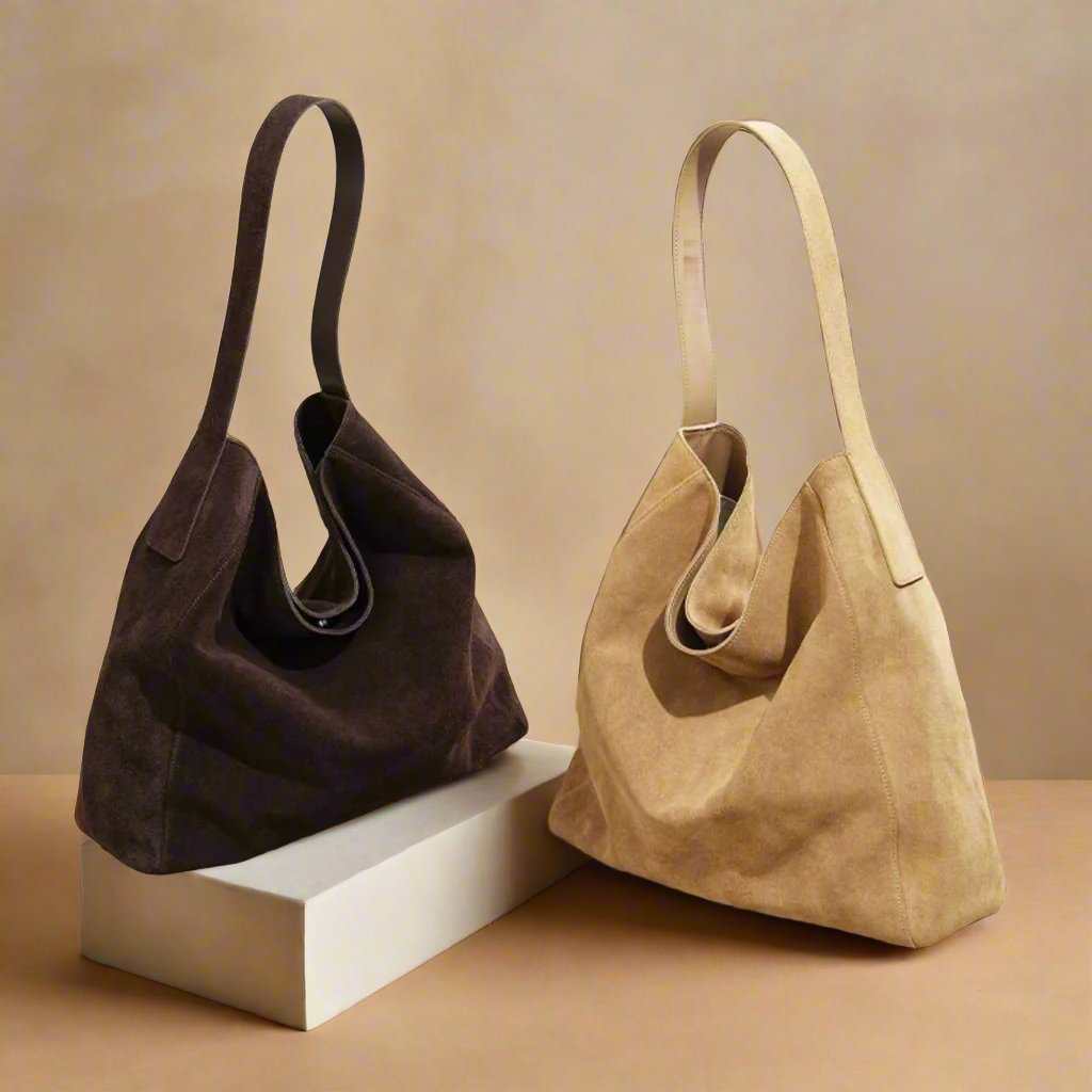 Suede slouch bag in dark and light shades displayed on a pedestal.