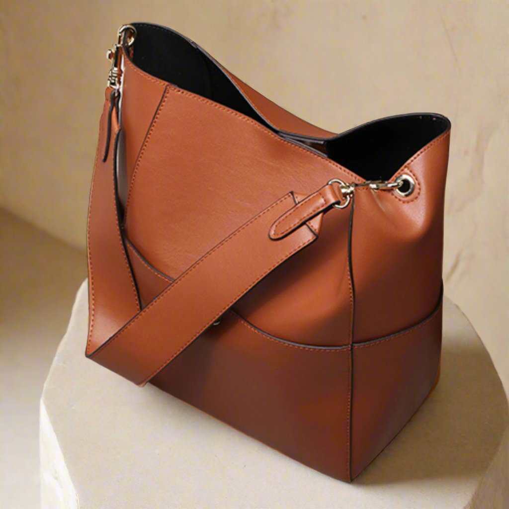 Elegant genuine leather women's bucket bag with reinforced shoulder strap and magnetic snap closure.