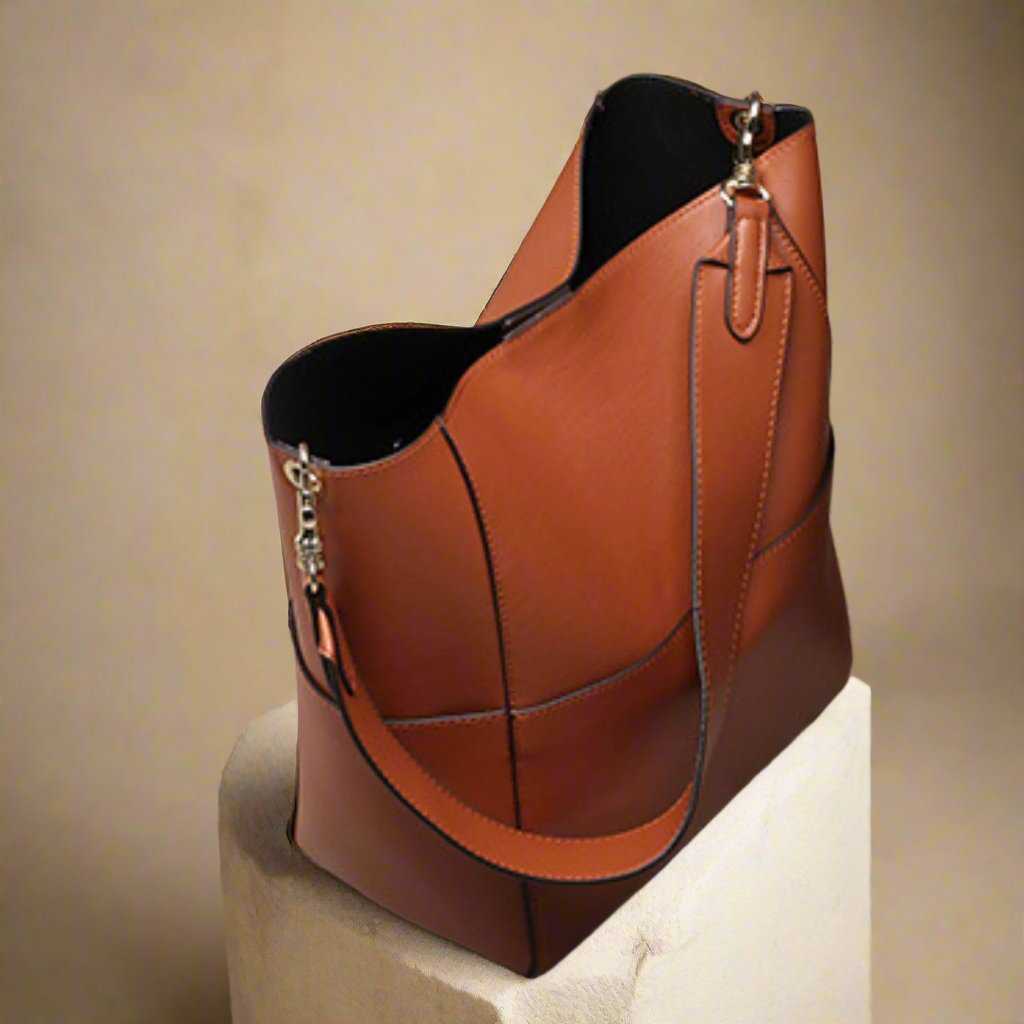 Elegant leather women's bucket bag with adjustable strap displayed on a pedestal.