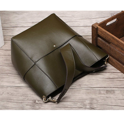 Genuine leather women's bucket bag with removable shoulder strap, shown on wood surface.