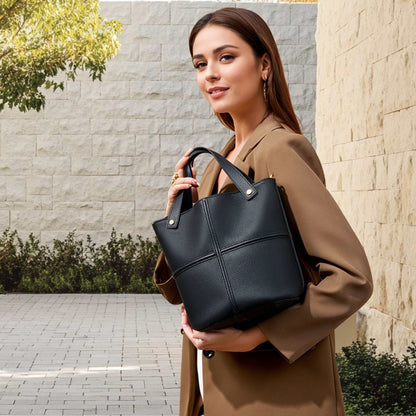 Woman holding black leather work bag in a professional setting.