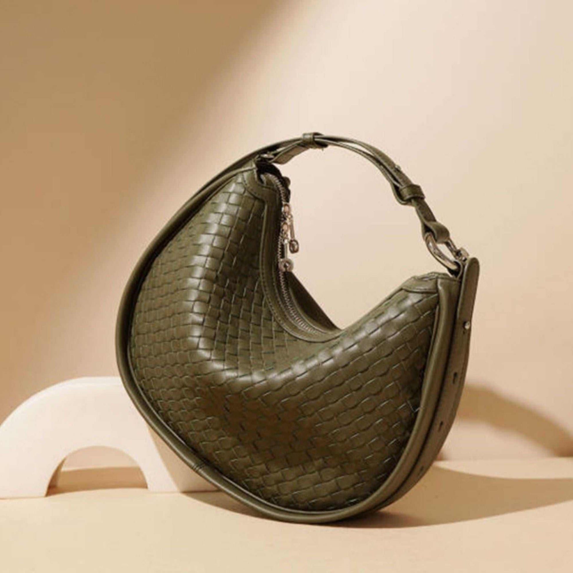 Sage green woven leather crossbody bag with adjustable strap and zippered interior pocket.