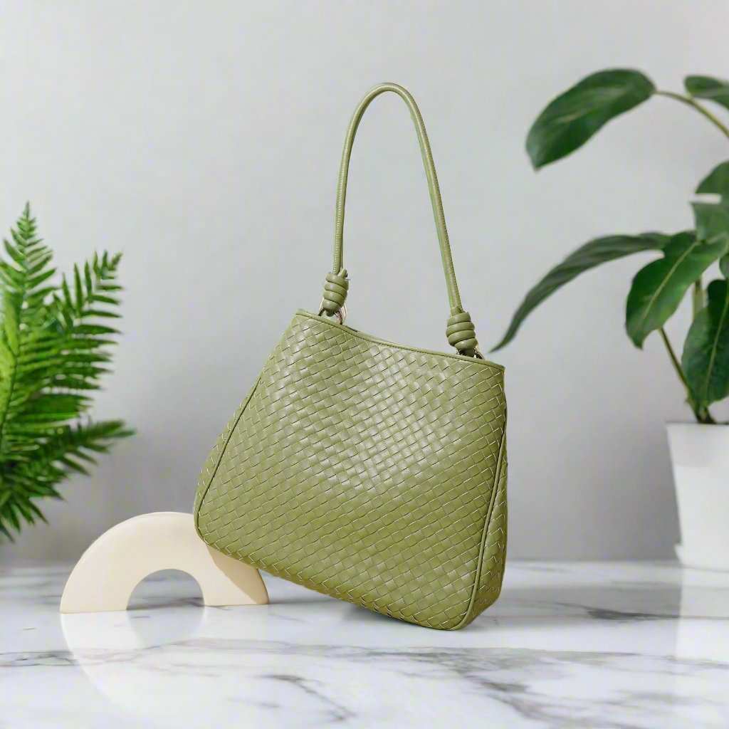 Woven Leather Tote Bag in Matcha Green on marble surface with plant decor.